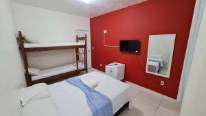 卡波布里奥Xodó do Peró Hostel的小房间设有一张床和红色的墙壁