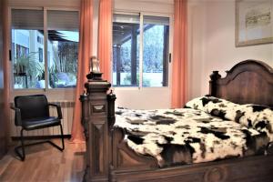 萨拉戈萨Casa con terrazas的一间卧室配有一张床、一把椅子和窗户。