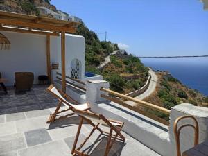 阿莫尔戈斯Idothea guest house的一张椅子坐在一个俯瞰大海的阳台上