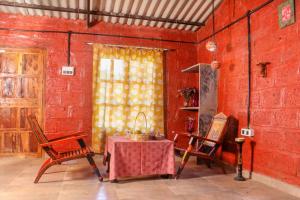 纳西克SiddhaDham - Farm Stay Cottage 1的配有桌椅和红色墙壁的房间