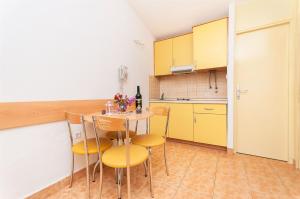 克勒克Apartments Bonaca的一间设有黄色橱柜和桌椅的小厨房