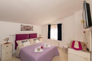 维泰博Casa Vacanze La Magnolia的一间卧室配有一张紫色的床和一台电视机