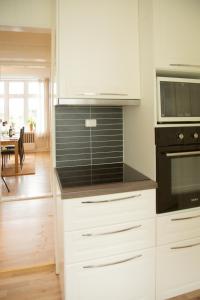 奥勒松Light Sentral Apartment Ålesund的厨房配有白色橱柜和黑色用具