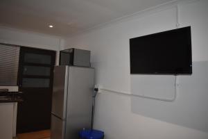 开普敦Langbeentjie Inn的带冰箱的厨房和平面电视。