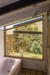 奥塔瓦洛Neblina Bird的浴室配有带浴缸和浴缸的窗户。
