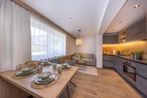 布鲁克安德格罗斯哥Lenni´s Apartments的厨房、带木桌的客厅和用餐室