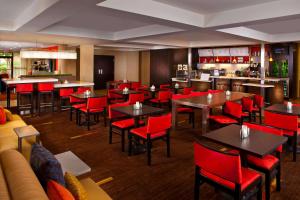 伯明翰伯明翰柱廊/汇景万怡酒店的一间带桌子和红色椅子的餐厅和一间酒吧