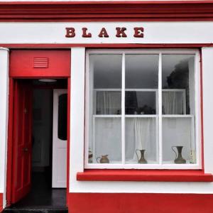 基尔基Blakes in Carrigaholt的红色和白色的建筑,带有窗户的标志,上面有闪烁的信号