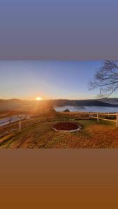 伊克斯雷玛Pousada Mirante de Minas的落日,在有栅栏和湖泊的田野上