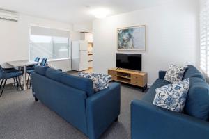 巴特曼斯贝Batemans Bay Lodge的客厅配有2张蓝色沙发和1台电视