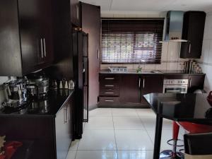 BrakpanCheerful Family Holiday Home的厨房配有棕色橱柜和黑色台面