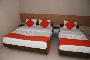 贾姆讷格尔Hotel Nawanagar Residency的配有红色和白色枕头的客房内的两张床