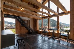 高山HAKU 100-year-old Quaint Japanese Style Villa的配有桌椅和大窗户的客房