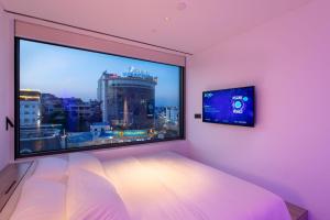下龙湾SOJO Hotel Ha Long的一间卧室设有大窗户和电视