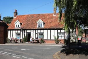 FoulshamThe Queens Head Glamping的坐在建筑物外桌子上的人