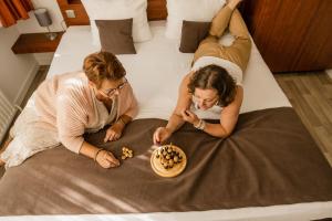 布鲁日Hotel Olympia in Bruges的两个女人躺在床上吃一碗食物