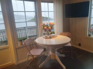 波多Idyllisk sjøhus på Naurstad的窗户房间里一张桌子上摆着鲜花和花瓶