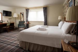 阿尼克The Hog's Head Inn - The Inn Collection Group的酒店客房设有一张白色大床和一张书桌
