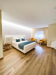 蓬德利马山坡旅馆的卧室配有一张白色的大床,铺有木地板