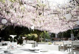 格拉纳达 帕拉西奥德洛斯帕托斯酒店的树下设有桌椅的餐厅,种有粉红色的花