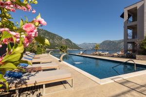 科托尔HUMA Kotor Bay Hotel and Villas的酒店游泳池设有躺椅,享有海景