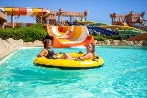 库塞尔Akassia Swiss Resort的两个女人在水上公园的一条内胎里骑着