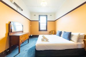 悉尼史卓菲酒店的一间卧室配有一张床、梳妆台和电视。