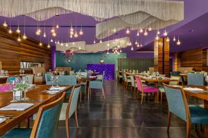 塞萨洛尼基Lazart Hotel, Trademark Collection by Wyndham的餐厅设有木桌、椅子和紫色天花板。