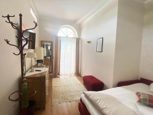 沃尔特湖畔佩莎赫阿斯托利亚酒店的一间卧室配有一张床、一张书桌和一个窗户。
