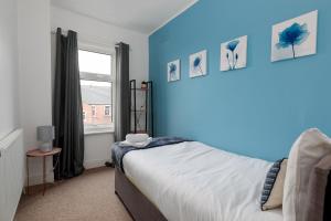 格兰瑟姆Spacious & Unique Family and Contractor House & Parking & A1 Road的一间卧室配有一张蓝色墙壁的床和一扇窗户