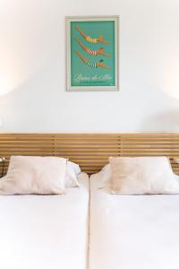 波城维多利亚花园波城公寓酒店的两张带白色枕头的床和一张墙上的照片