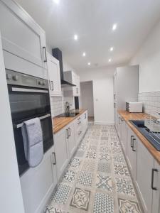 巴罗弗内斯Highly Modern home, 3 bed, close to the Lake District的厨房配有白色橱柜和瓷砖地板。