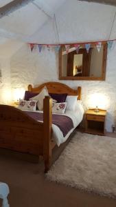 卡姆尔福德Mayrose Cottage, Charming Cornish Cottage for the perfect escape...的一间卧室配有木床和镜子