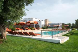 奥斯图尼Masseria Santo Scalone的游泳池旁的游泳池配有椅子和遮阳伞