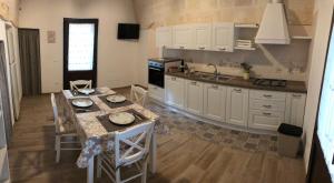 莫诺波利Le Stelle di Nonna Anna的厨房配有白色橱柜和桌椅