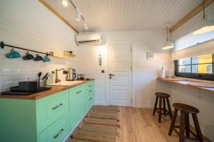 卡斯ROOT TINY HOUSE KALKAN的厨房配有绿色橱柜和带凳子的台面