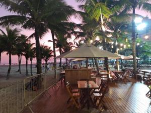 大普拉亚Solar Canto do Forte的海滩上拥有桌椅和棕榈树的餐厅
