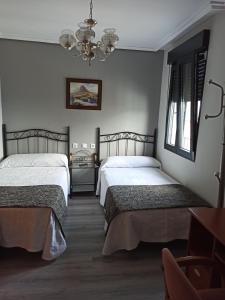 FaberoPENSION LA PARADA的一间卧室配有两张床和吊灯。