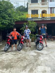 河江HG Hostel and Motorbikes的三人站在他们摩托车旁的一座建筑前