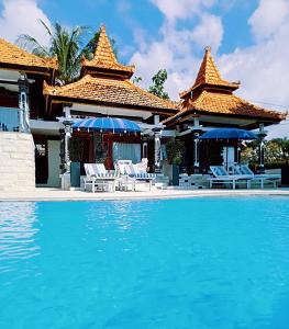 BanjarSoul Lodge Villa Lovina的毗邻度假酒店的带椅子和遮阳伞的游泳池