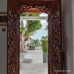 BanjarSoul Lodge Villa Lovina的华丽的木门通往棕榈树庭院