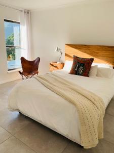 开普敦BEAUTIFUL VIEW Garden Apartment的一间卧室配有一张大床、椅子和窗户