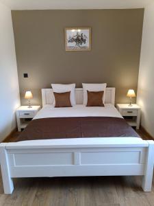 BoussièresGîtes de l'Orée du Bois的卧室配有一张带两张桌子的大型白色床