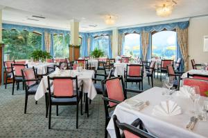 法克湖畔杜罗博拉赫施翁鲁酒店的一间设有白色桌椅的用餐室