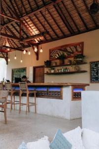 龙目岛库塔Jati Kuta Lombok的餐厅内的酒吧配有桌椅