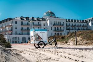 于斯德Strandhotel Kurhaus Juist的停在海滩上的自行车停在大楼前