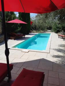 克尔克Villa Splendissima Krk - Adults only的一个带红色遮阳伞和红色椅子的游泳池