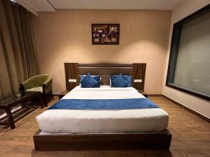 阿姆利则AH1 Hotel的一间卧室配有一张带蓝色枕头的大床