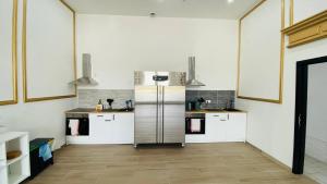 那慕尔BED Cauchy的厨房配有白色橱柜和不锈钢冰箱