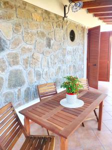 利帕里Holiday home Mennulita的一张木桌、两把椅子和石墙